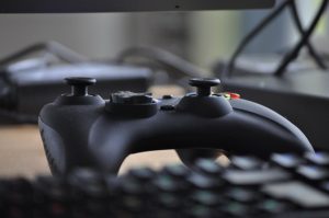 An xbox 360 controller sat next to a keyboard on a desk