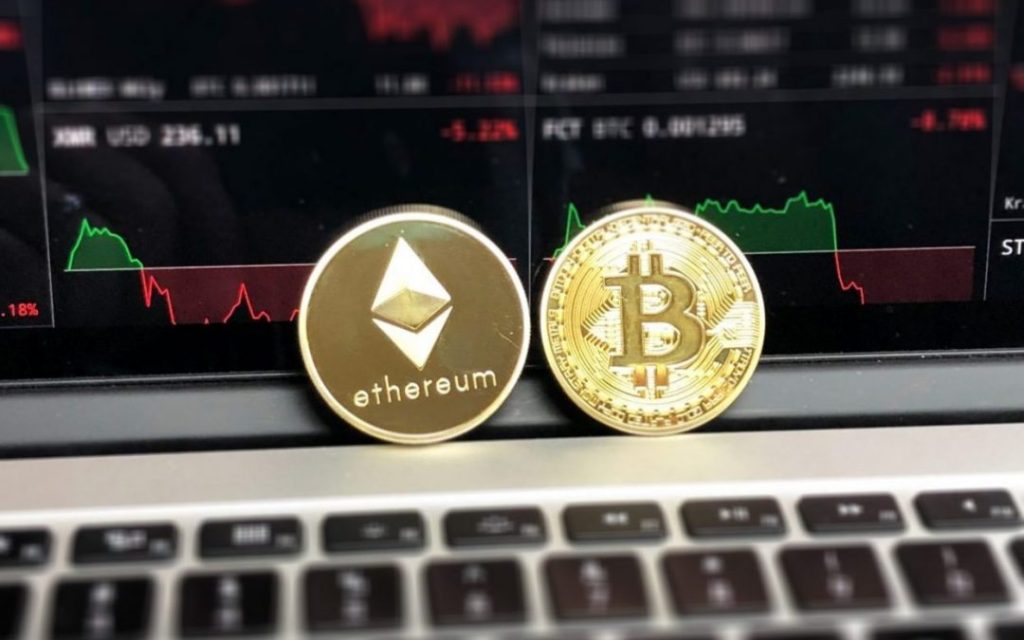 Ethereum and Bitcoin cryptocurrency sitting on a laptop