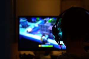 Cheating Gamer Kid playing video game with headset on likely a streamer, possibly playing to relieve stress and make new friendships