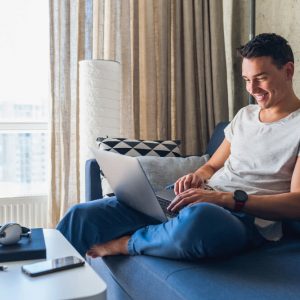 Young attractive man using the internet wearing a smartwatch and using Google Drive for communications