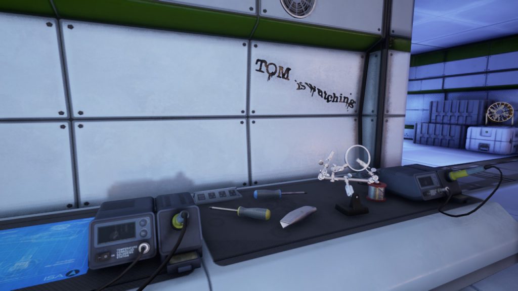 The Turing Test work bench with message "Tom is watching" scrawled on the wall