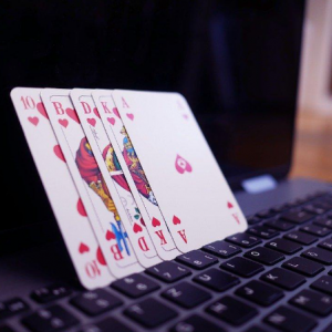 Poker cards rested on laptop showing a Royal Flush