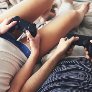 Adult Gamer Couple with PlayStation controllers playing their favourite game genres