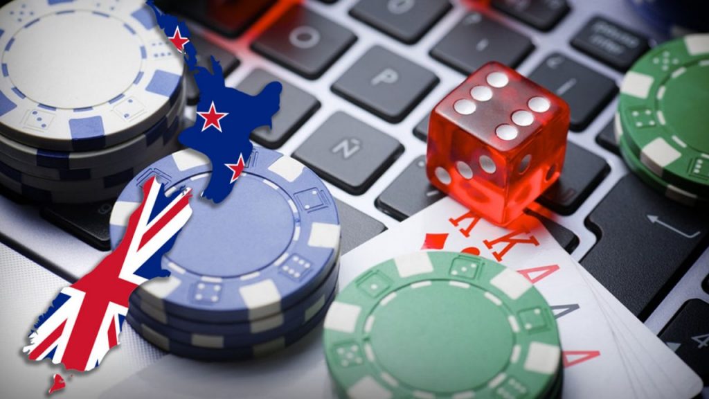 New Zealand poker chips, cards and a die on a laptop keyboard