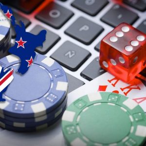New Zealand poker chips, cards and a die on a laptop keyboard