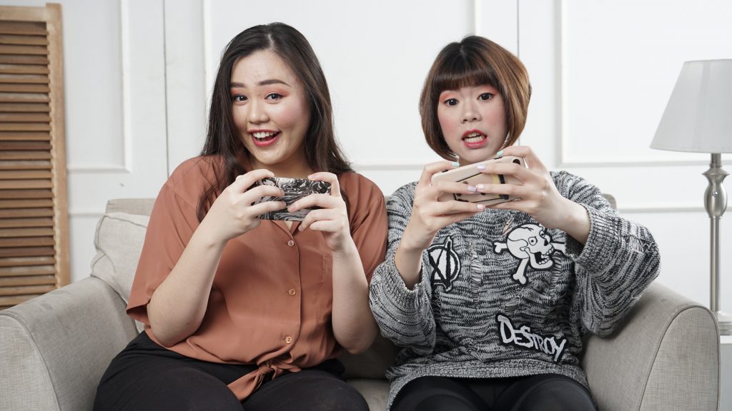 Two Asian Female Gamers Playing on their phones