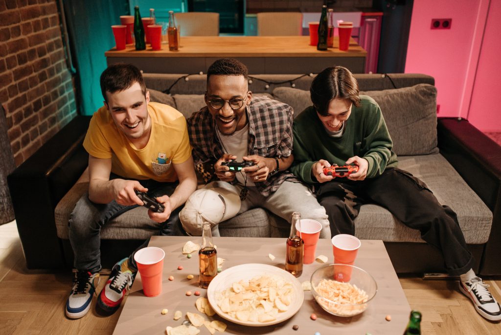 Three friends playing video games together on a couch