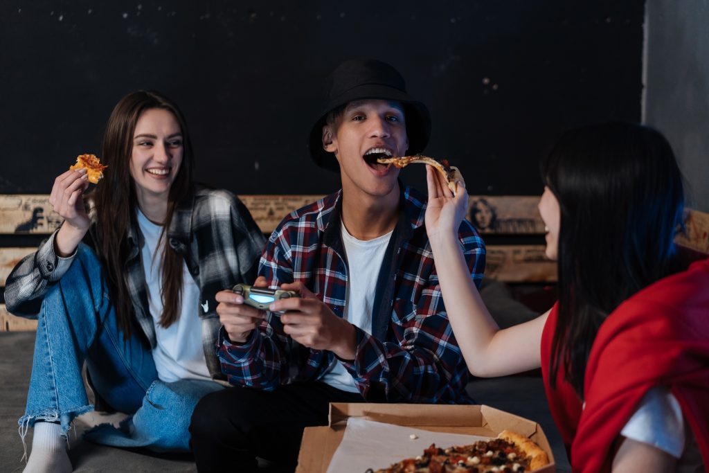 A man being fed food while playing games.