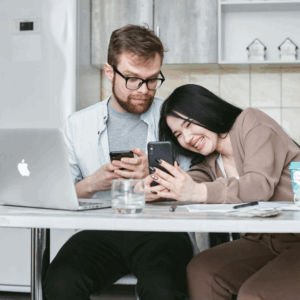 Couple on phones sat at a desk having a micro-moment